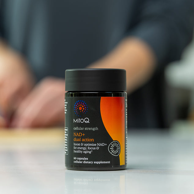 MitoQ NAD+ dual action supplement container on a table with a blurred background