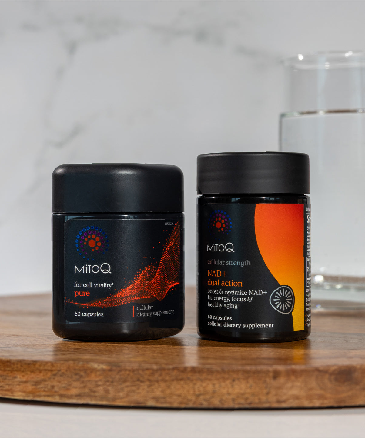 Two MitoQ supplement containers, MitoQ Pure and MitoQ NAD+ dual action, on a wooden surface with a blurred background